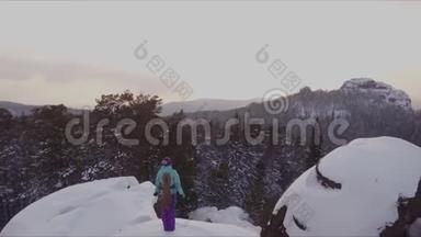 一位年轻的女登山者站在山顶上看日落。